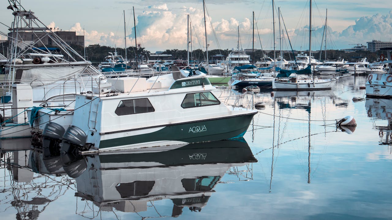 Tranquil marina with docked boats reflecting on calm water.